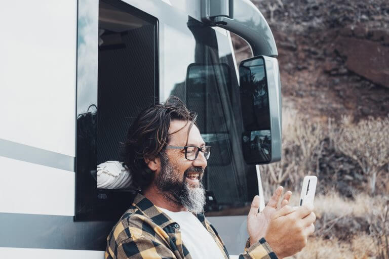 Happy tourist with camper van use mobile phone to call and speak remote friends with voice and internet connection in the country side. Roaming online technology and travel lifestyle people