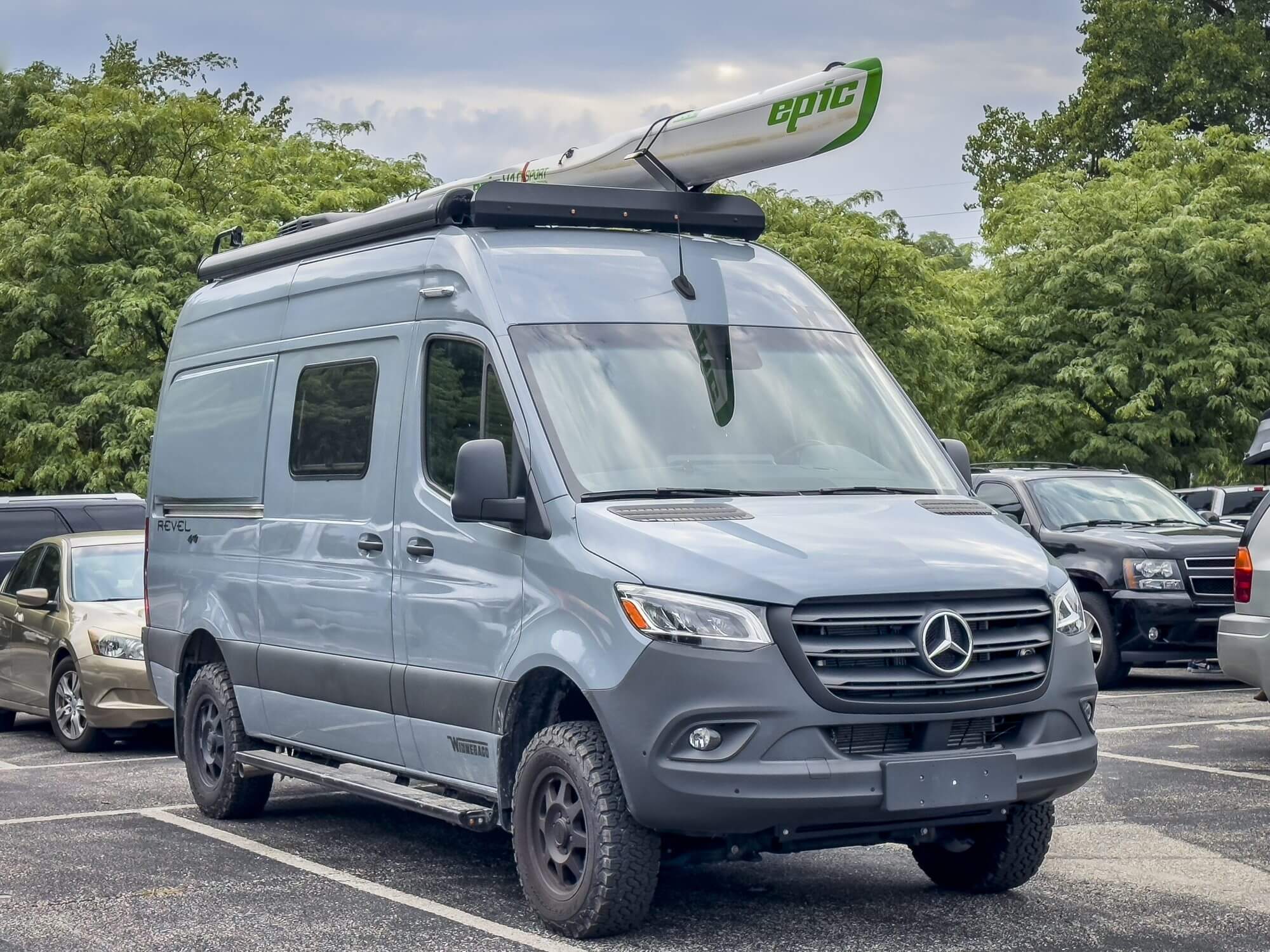 St Charles, MO, USA - August 4, 2023: Winnebago Revel camper van on Mercedes Sprinter chassis with Epic kayak or surfski on roof racks.