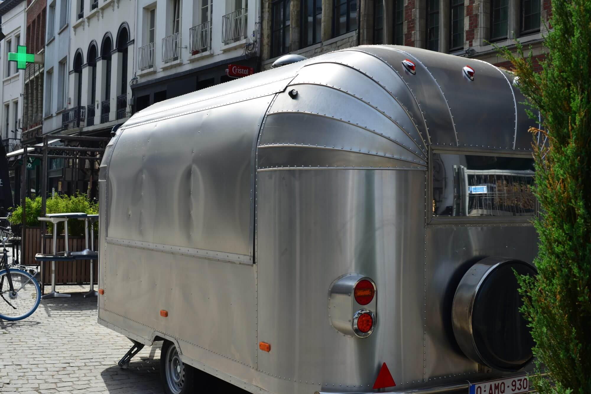 Antwerp city, Province Antwerp, Belgium - June 18, 2022: stationary aluminium design caravan mobile home round shapes closed window shutters stationary abandoned in front of row houses