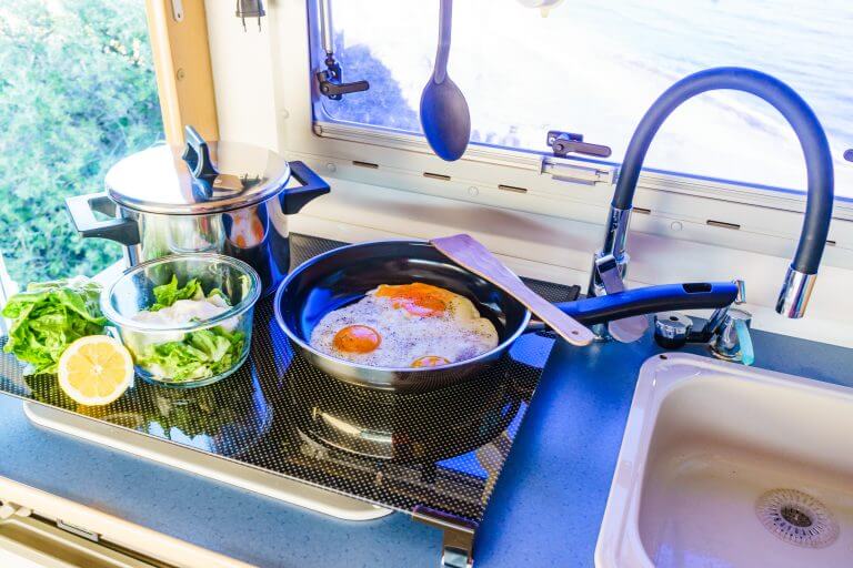 Caravan rv inside, kitchen area. Cooking dinner meal in campervan. Holidays, adventure with motor home. Van life lifestyle.