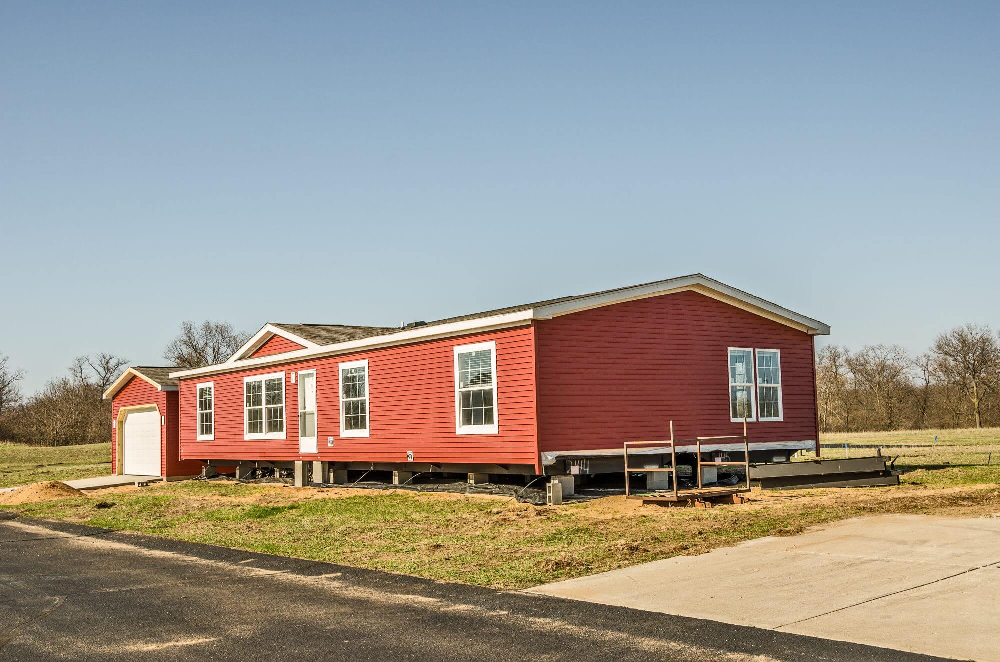 New manufactured home with red vinyl siding and windows with white lineals