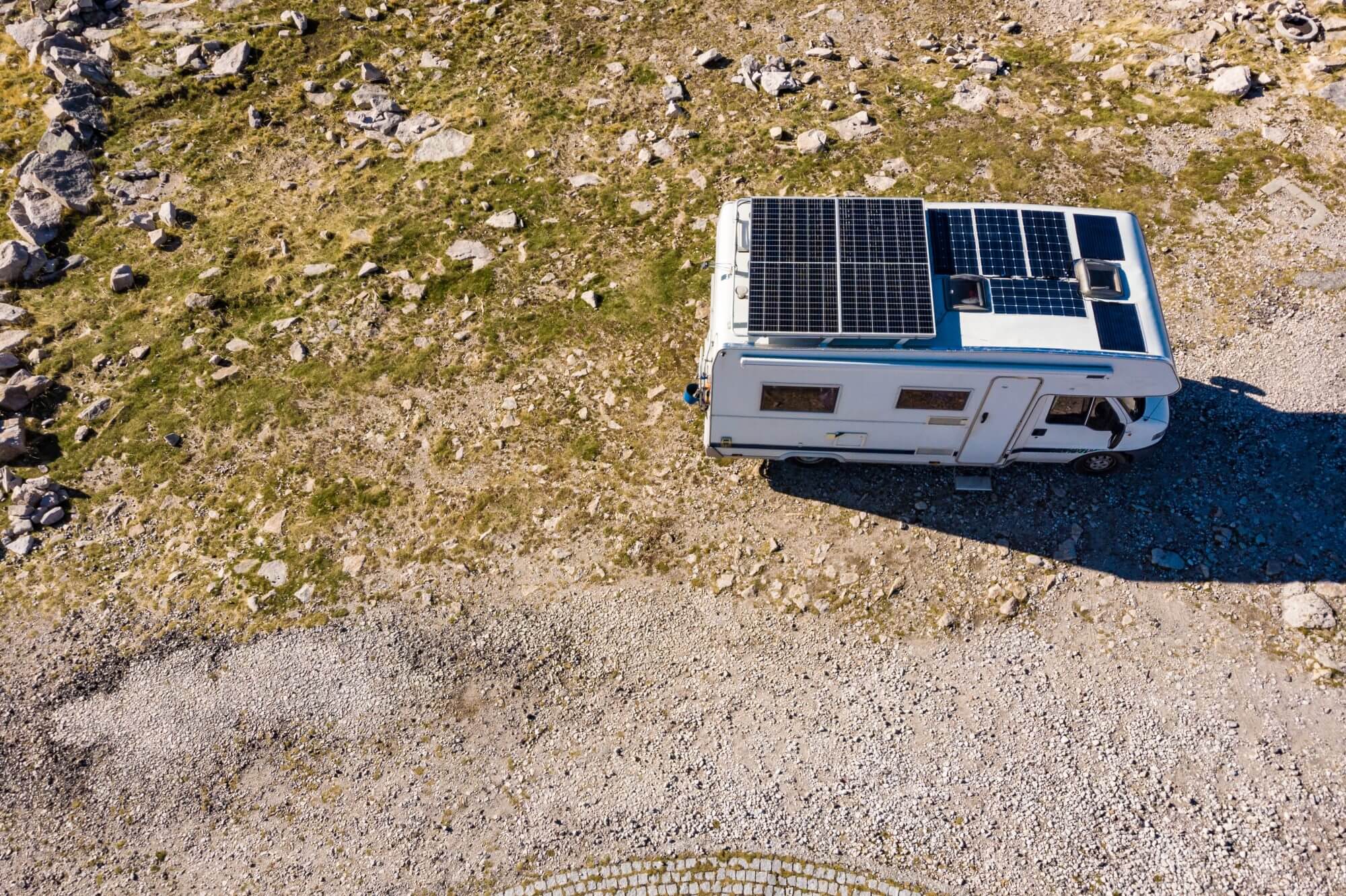 Aerial view of camper with many solar photovoltaic panels on roof camping on nature. Renewable free energy. Elecrticity on caravan holidays.