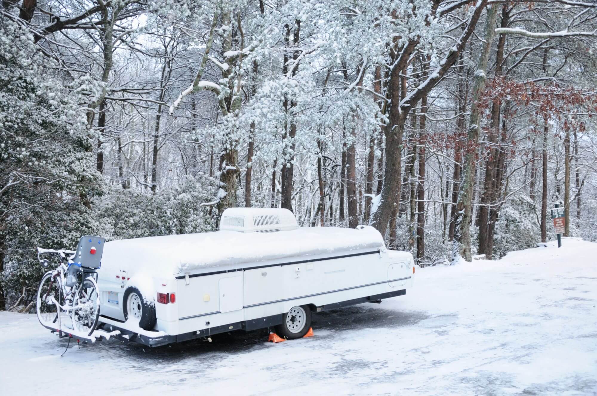 "Recreational vehicle pop up camper in storage covered by snow, horizontal with copy space."