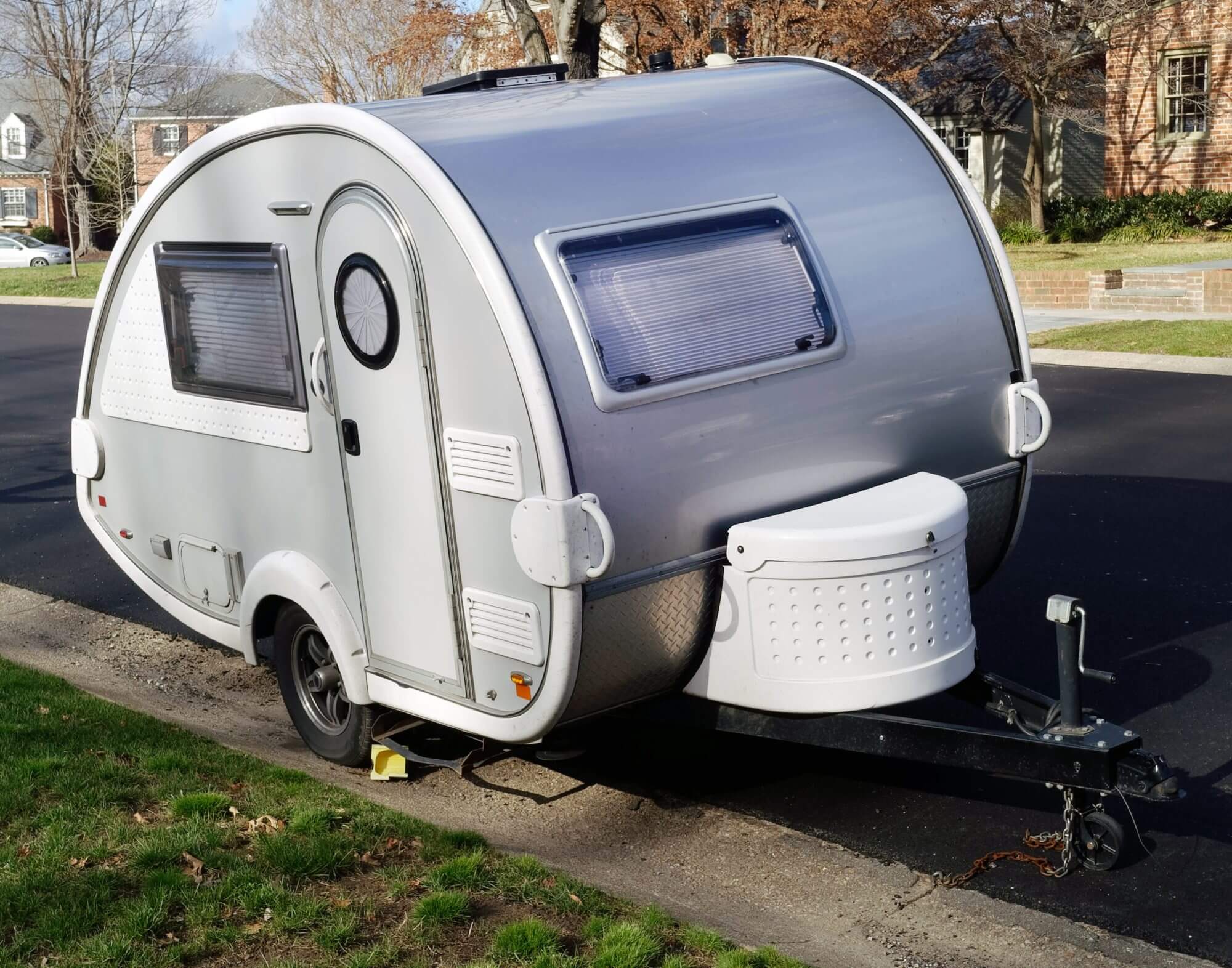 Cute teardrop shaped camping trailer parked in residential neighborhood.