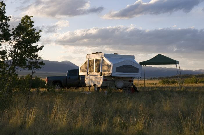 small pop-up camper sitting in an open meadow in the southern mountains of Colorado.