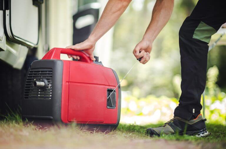 Caucasian Men Firing Portable Inverter Generator to Electrify RV Camper Van During Dry Camping. RV Boondocking with Own Small Electricity Gas Powered Plant.