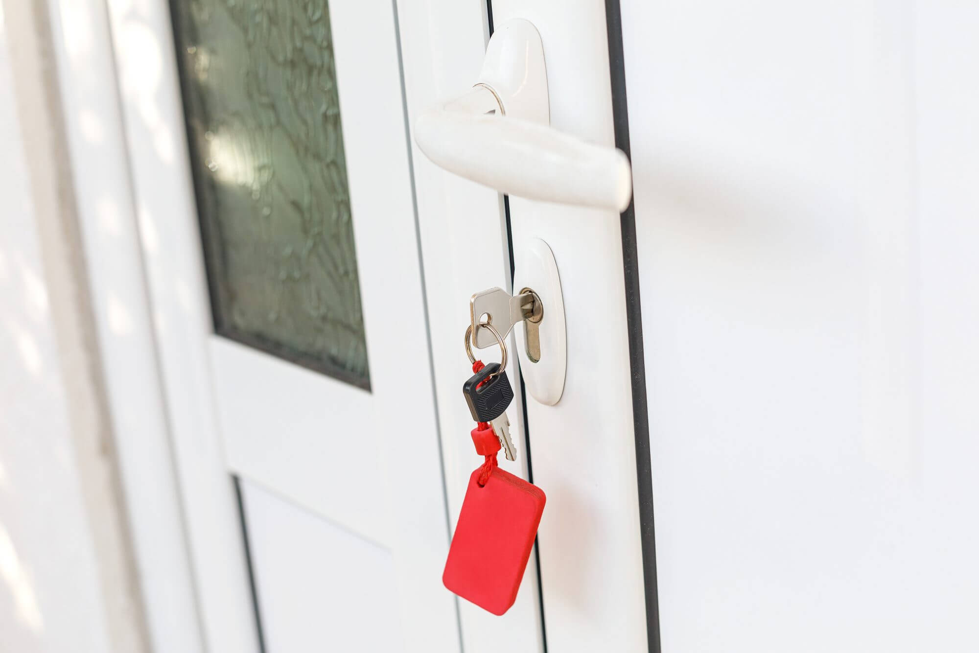 White plastic handle or doorknob and lock with key of closed house door