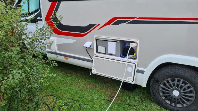 Camper parks on a camper place and fills up fresh drinking water for the next trip