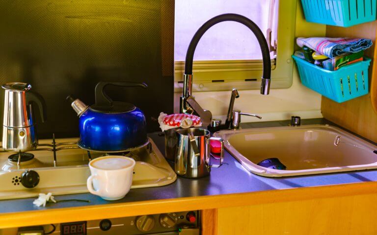 Caravan rv inside, kitchen area. Preparing coffee in moka pot on stove. Holidays, adventure with motor home. Van life lifestyle.
