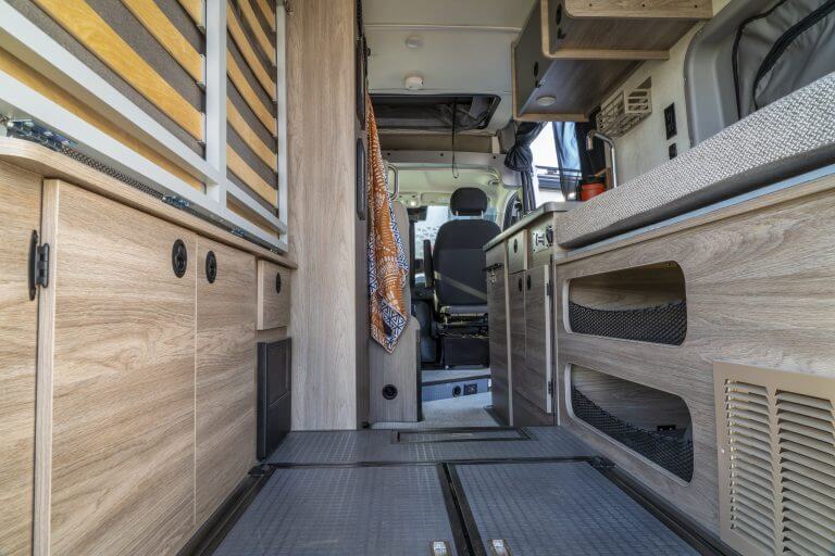 interior of camper van with cargo area, folded bed and kitchen