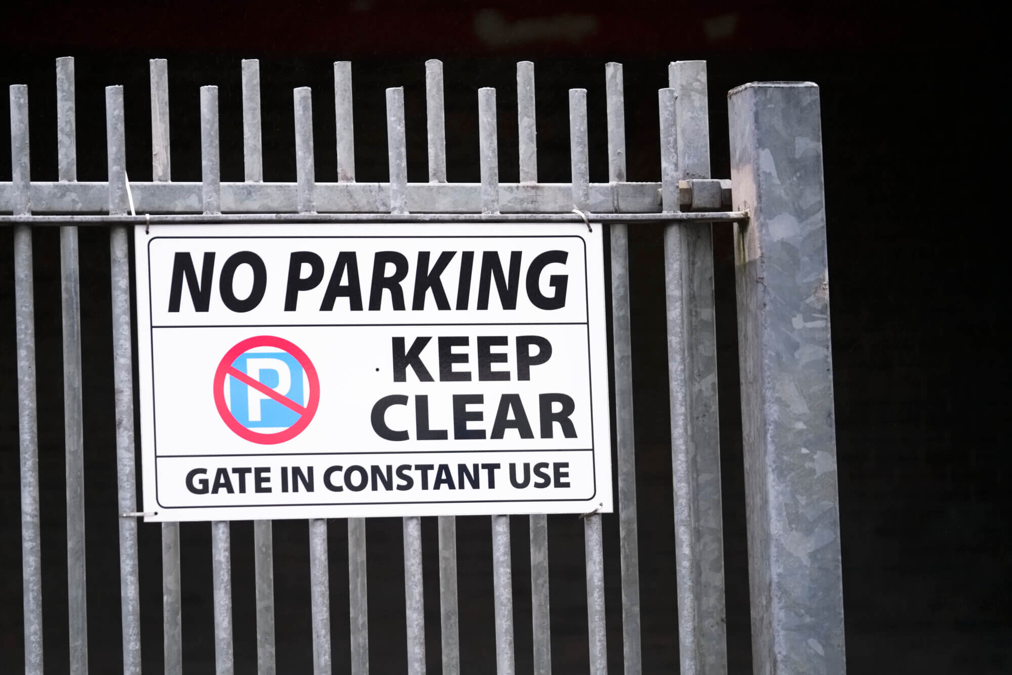 No parking keep clear sign with gate entrance door at constant use uk