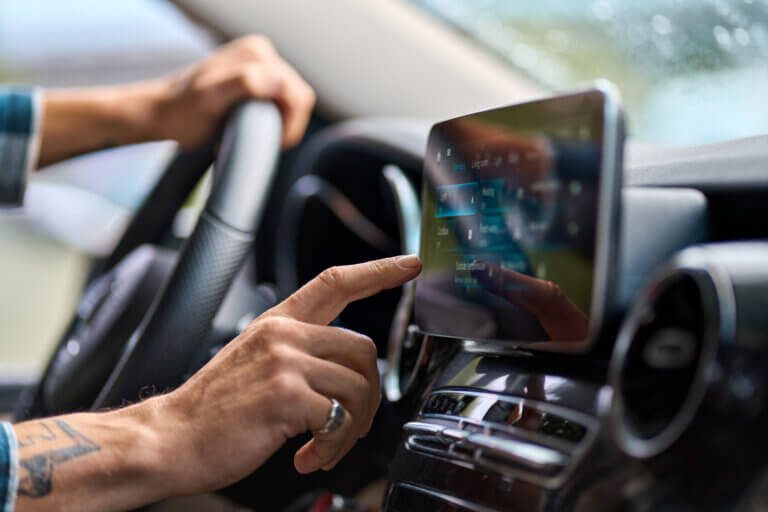 Older man sitting in camper van using gps navigation map system digital device. Smiling mature active traveler driving car vehicle looking at screen touching sensor gadget dashboard, close up view.