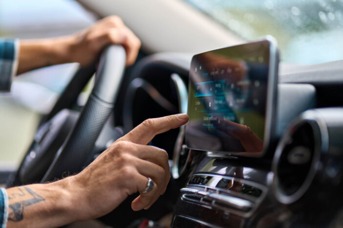 Older man sitting in camper van using gps navigation map system digital device. Smiling mature active traveler driving car vehicle looking at screen touching sensor gadget dashboard, close up view.
