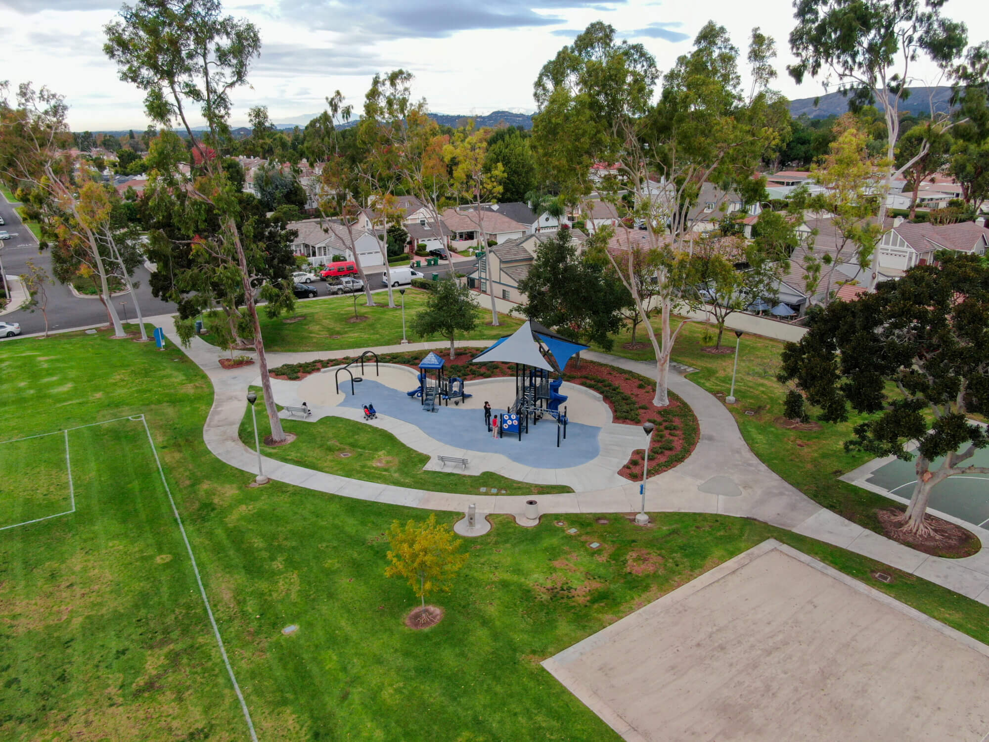 Aerial view of little park in Suburban packed homes neighborhood with road. Vast subdivision in Irvine, California, USA