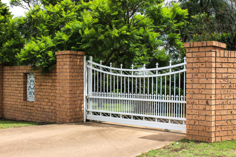 White wrought iron entrance gate set in brick fence