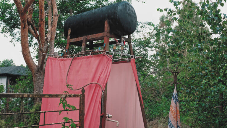 Summer Camp Improvised Outdoor Shower with Black Painted Water Tank Heated with Solar Energy