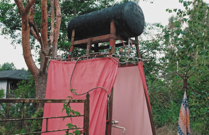 Summer Camp Improvised Outdoor Shower with Black Painted Water Tank Heated with Solar Energy
