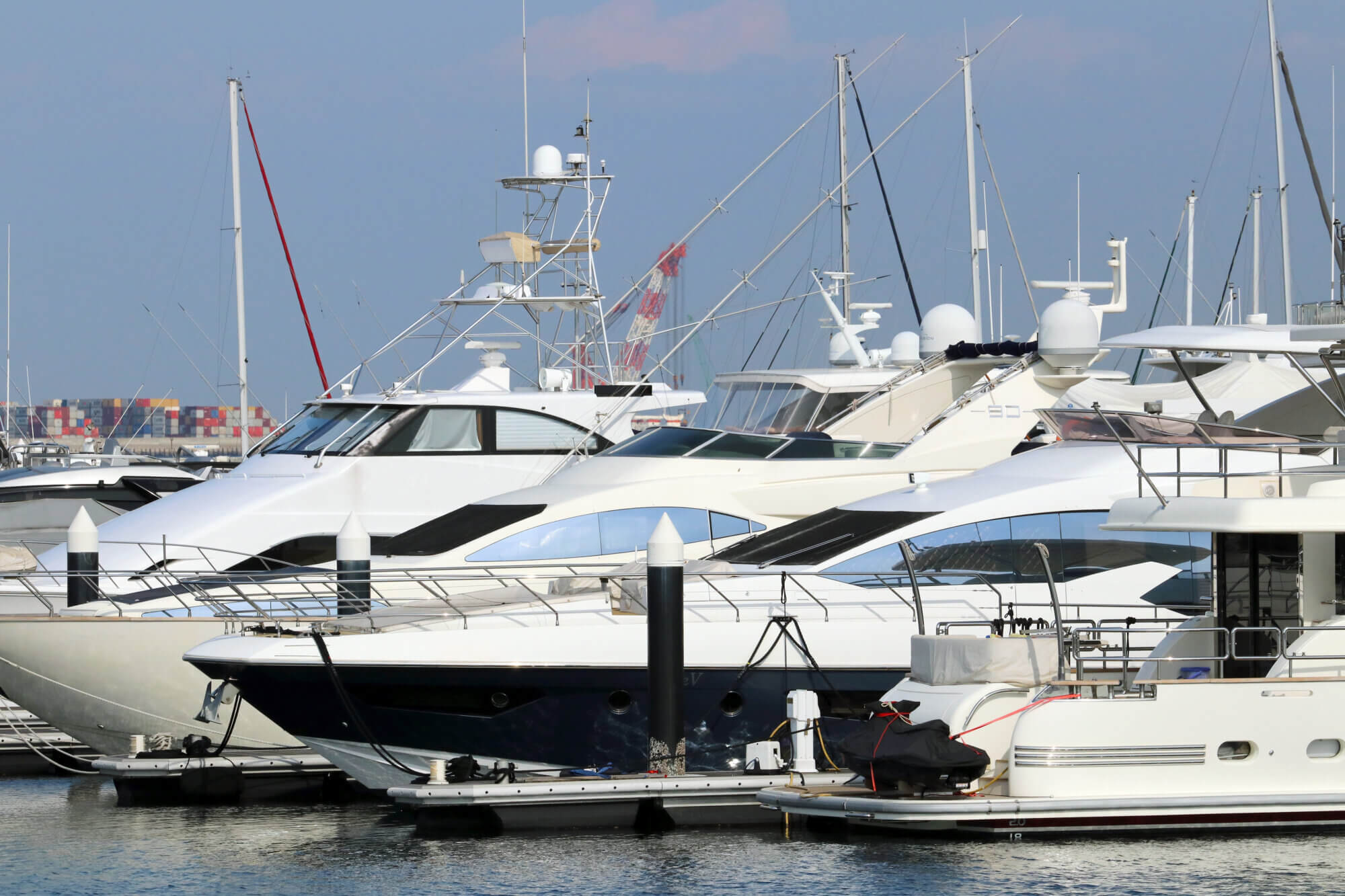 Boats in marina photography taken under the warm afternoon sun light. Yachts and pleasure boats moored in the marina on a sunny day.