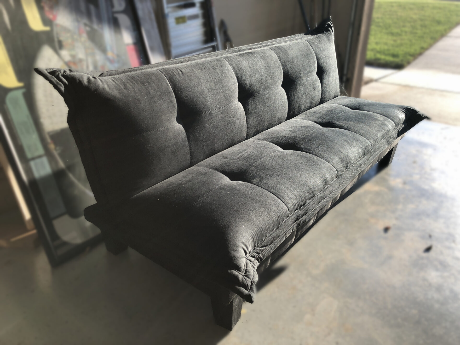 Black foldable futon bed set out in a garage