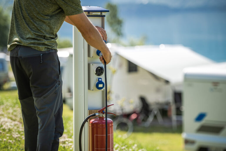 Motorhome RV Owner Attaching Power Cable to Camping Electric Post During Camping Stay