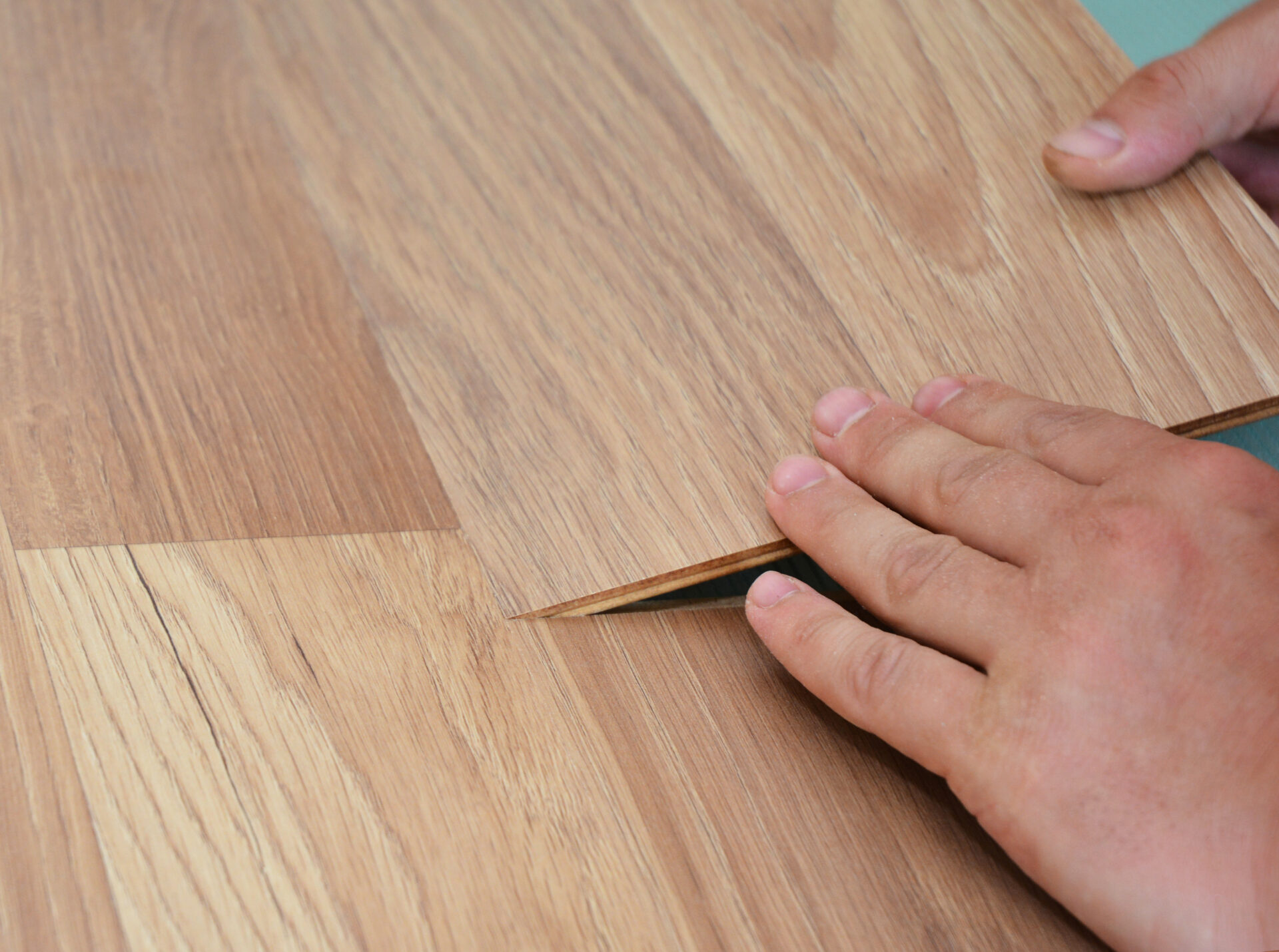 A close-up on a handyman, DYIer installing floating laminate floor, wood <a href=